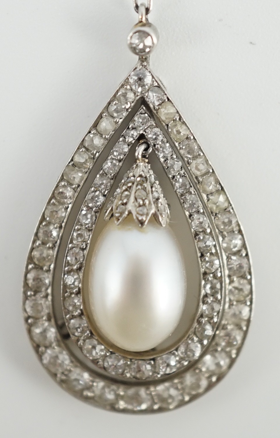 An early 20th century platinum, cultured? pearl and diamond cluster set pear shaped drop pendant necklace